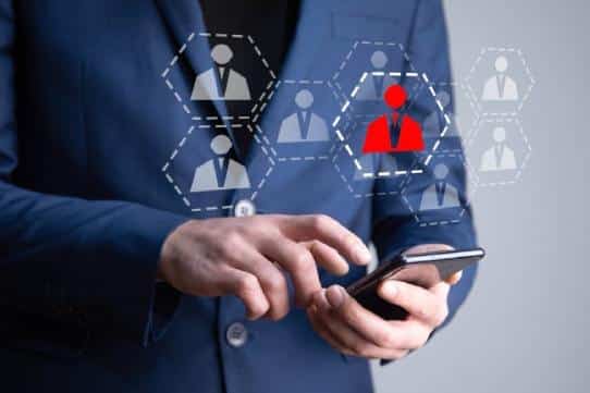 ```json { "alt": "Person in a suit using a smartphone with a digital illustration of connected user icons.", "title": "Businessman Using Smartphone with Digital User Icons" } ```