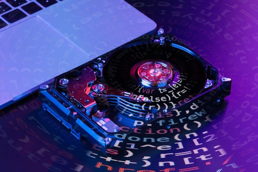 Hard drive with visible internal components and digital code overlay, representing data recovery services and IT solutions.