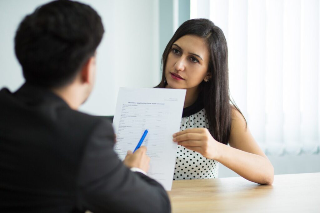 Young female manager discussing a business contract with a partner, emphasizing the importance of compliance in financial reporting related to the Sarbanes-Oxley Act.